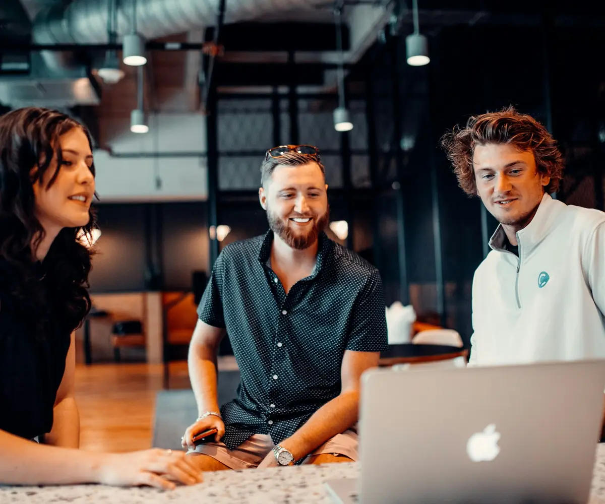 A consulting team working together around a laptop